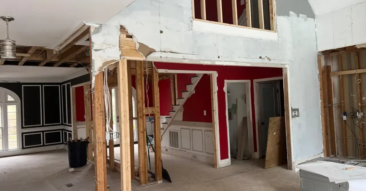 Démolition d'un mur non porteur, révélant la structure en bois et les fils électriques. Travaux de rénovation en cours.