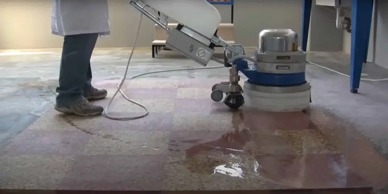 Une machine professionnelle est utilis&eacute;e pour poncer un carrelage, laissant une surface humide et propre.
