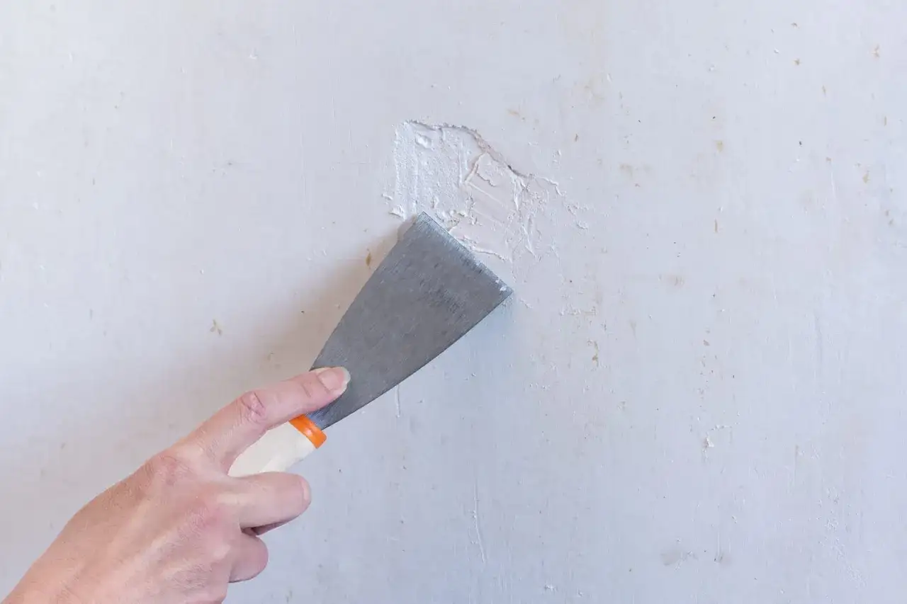 Maintenant, je r&eacute;pare un trou dans le mur avec une spatule et du mastic.