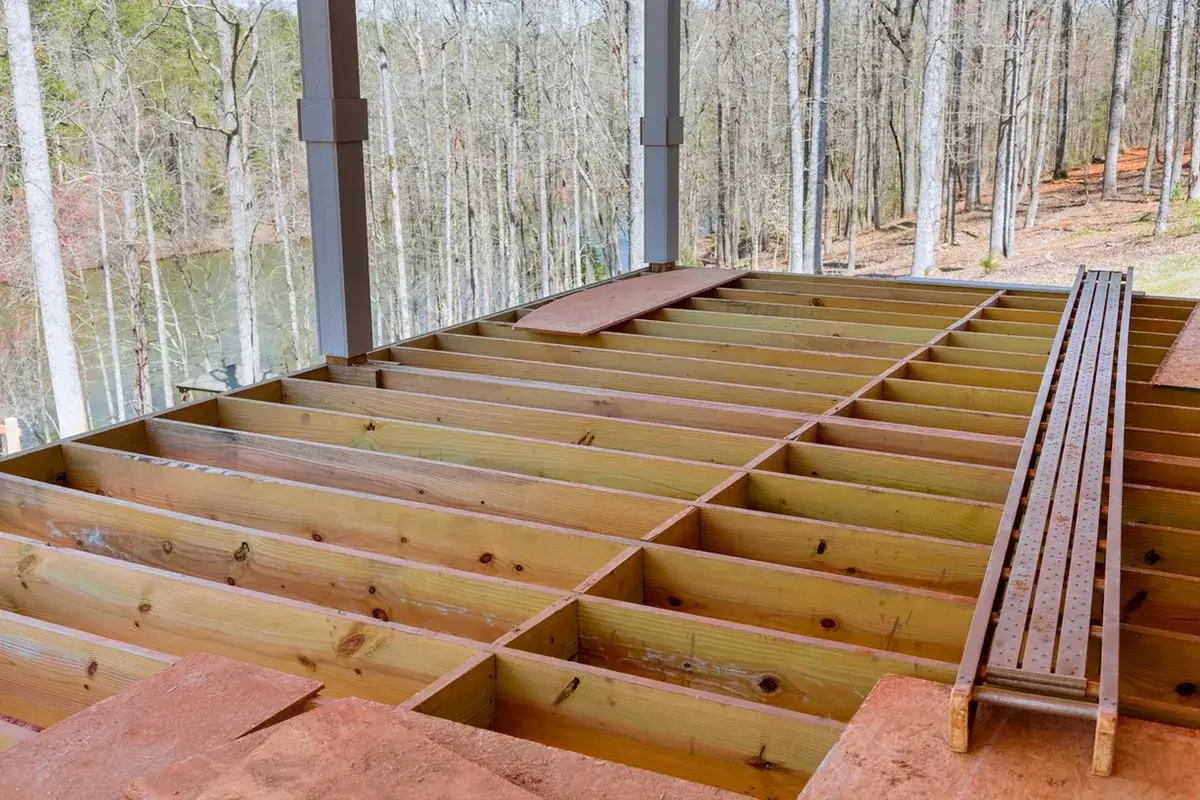 Structure en bois pour faire un plancher, pr&ecirc;te pour les lames. Vue sur la for&ecirc;t et un plan d'eau.