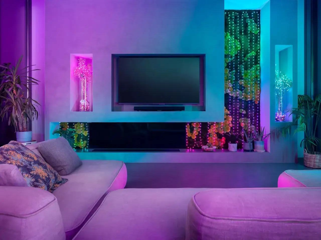 Un salon moderne aux lumi&egrave;res d'ambiance color&eacute;es. Le t&eacute;l&eacute;viseur est &eacute;teint, entour&eacute; de plantes et de guirlandes lumineuses. C'est quoi les lumens ? C'est la mesure de la lumi&egrave;re.