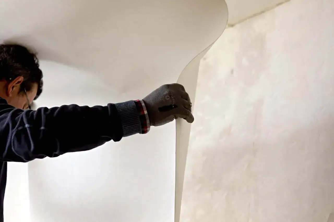 Un homme ganté pose une toile de verre sur un mur.