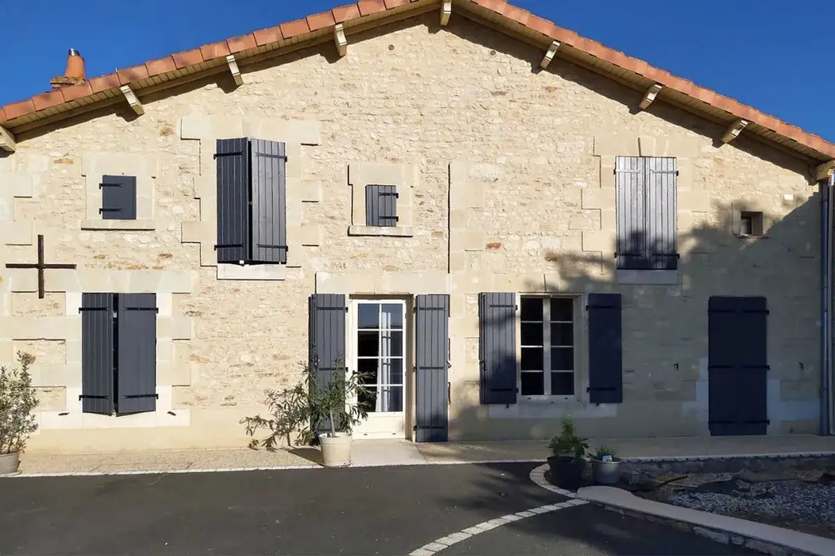 Maison en pierre avec une installation de volets battants gris anthracite, apportant une touche moderne &agrave; l'ensemble.