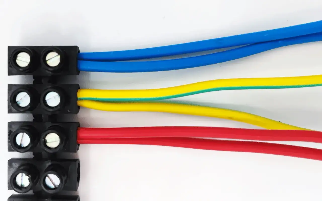 Trois fils &eacute;lectriques (bleu, jaune/vert, rouge) connect&eacute;s &agrave; des dominos &eacute;lectriques. L'installation &eacute;lectrique est interdite sans pr&eacute;cautions.