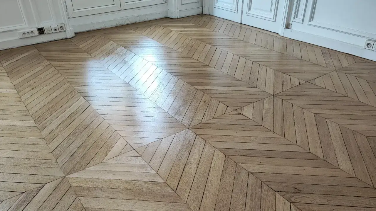 Parquet en bois clair, motif géométrique complexe. Le travail de rabot parquet révèle la beauté naturelle du bois.