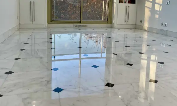 Sol en marbre blanc poli, orné de carreaux noirs, reflétant la lumière. Une rénovation marbre réussie qui illumine la pièce.
